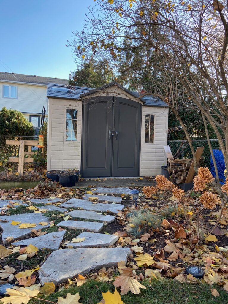 Charming Garden Shed: Nestled in a corner with a flagstone pathway leading to its entrance, adding a touch of rustic elegance to the garden.