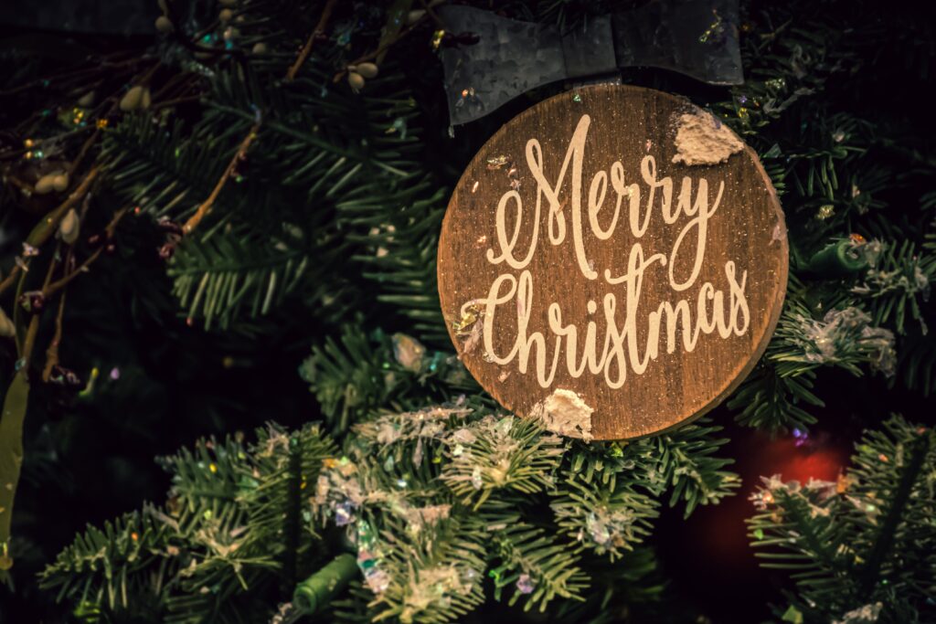 An ornament on a Christmas tree with the text 'Merry Christmas'.